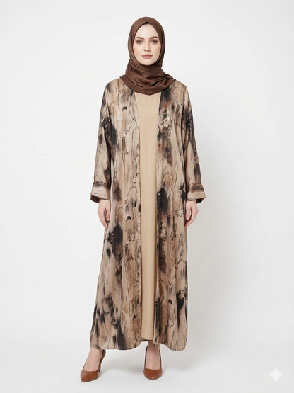 Fair-skinned model with grey eyes wearing the Rizqé Sandstone Marble-print beige satin kimono abaya with a matching tan inner dress and brown scarf against a solid white studio background.