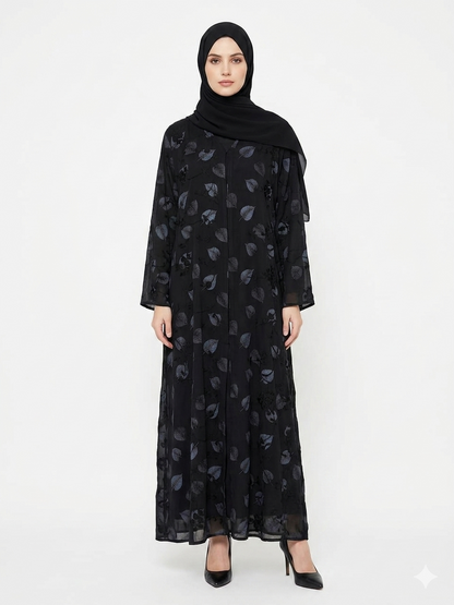 Fair-skinned model with grey eyes wearing the Rizqé Midnight Foliage black leaf-printed abaya with all-over thread embroidery and a matching black hijab against a solid white studio background.