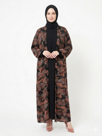 Fair-skinned model with grey eyes wearing the Rizqé Chocolate & Black Pashmina Print Nida abaya featuring a black front panel and full printed back against a solid white studio background.